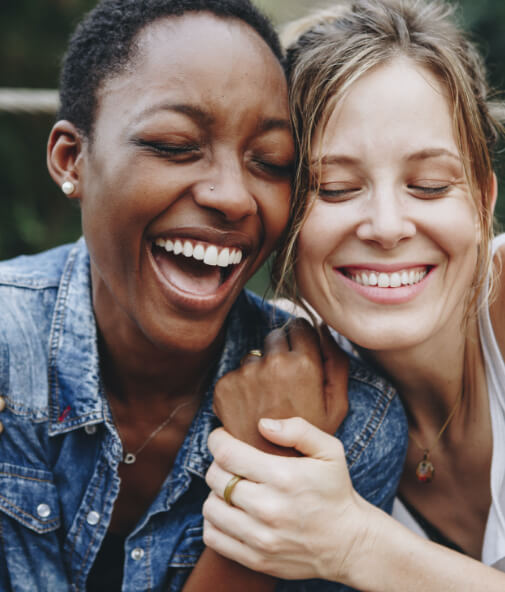 Two women smiling together after all ceramic dental restorations