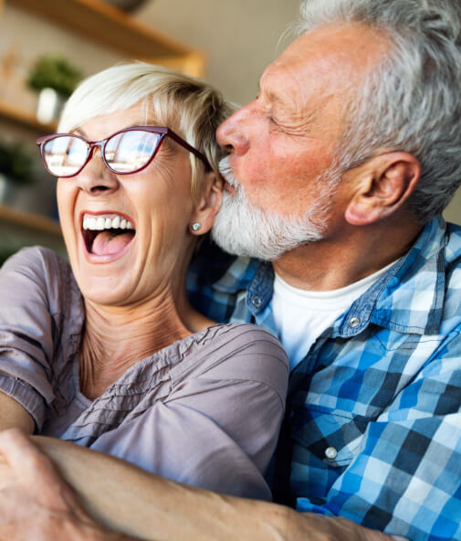 Man and woman laughing together after dental implant tooth replacement