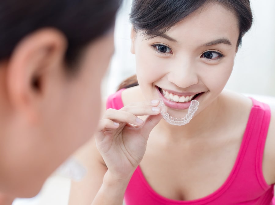 Woman placing her Invisalign clear aligner tray