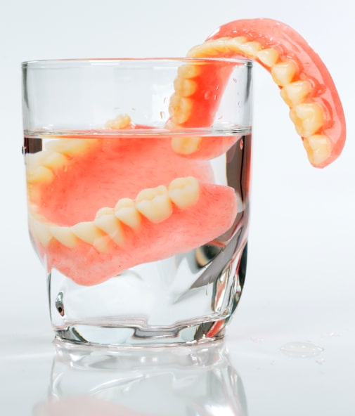 Set of dentures in glass of water