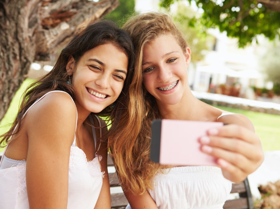 Two teens smiling during orthodontics treatment