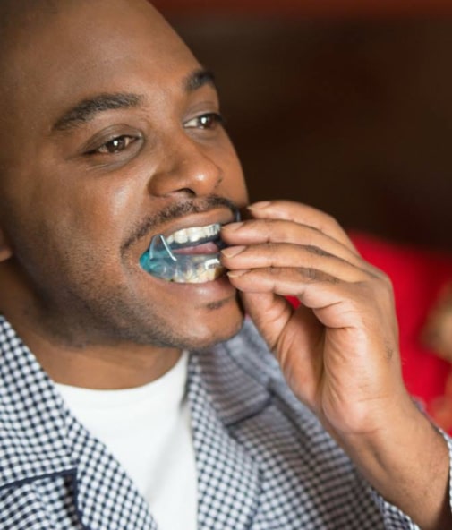 Man placing oral appliance for snoring prevention and sleep apnea treatment