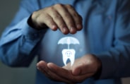 Hands holding an animated tooth under an umbrella